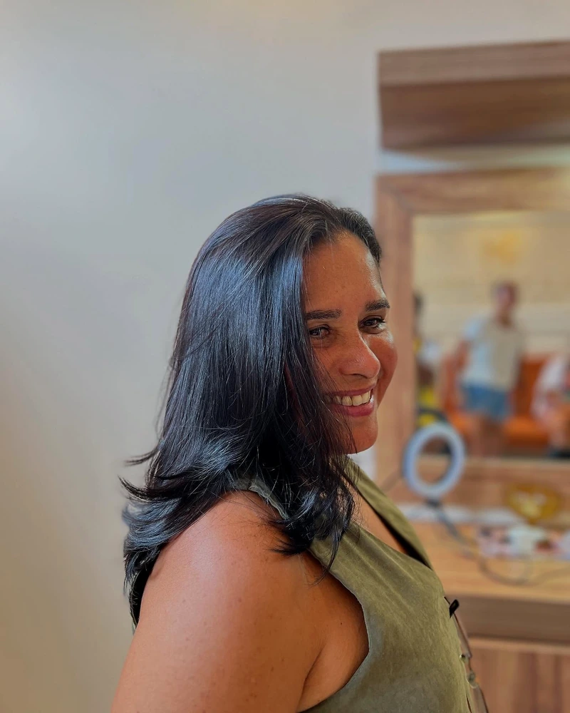 Cliente sorrindo com cabelo curto escuro, usando blusa verde.