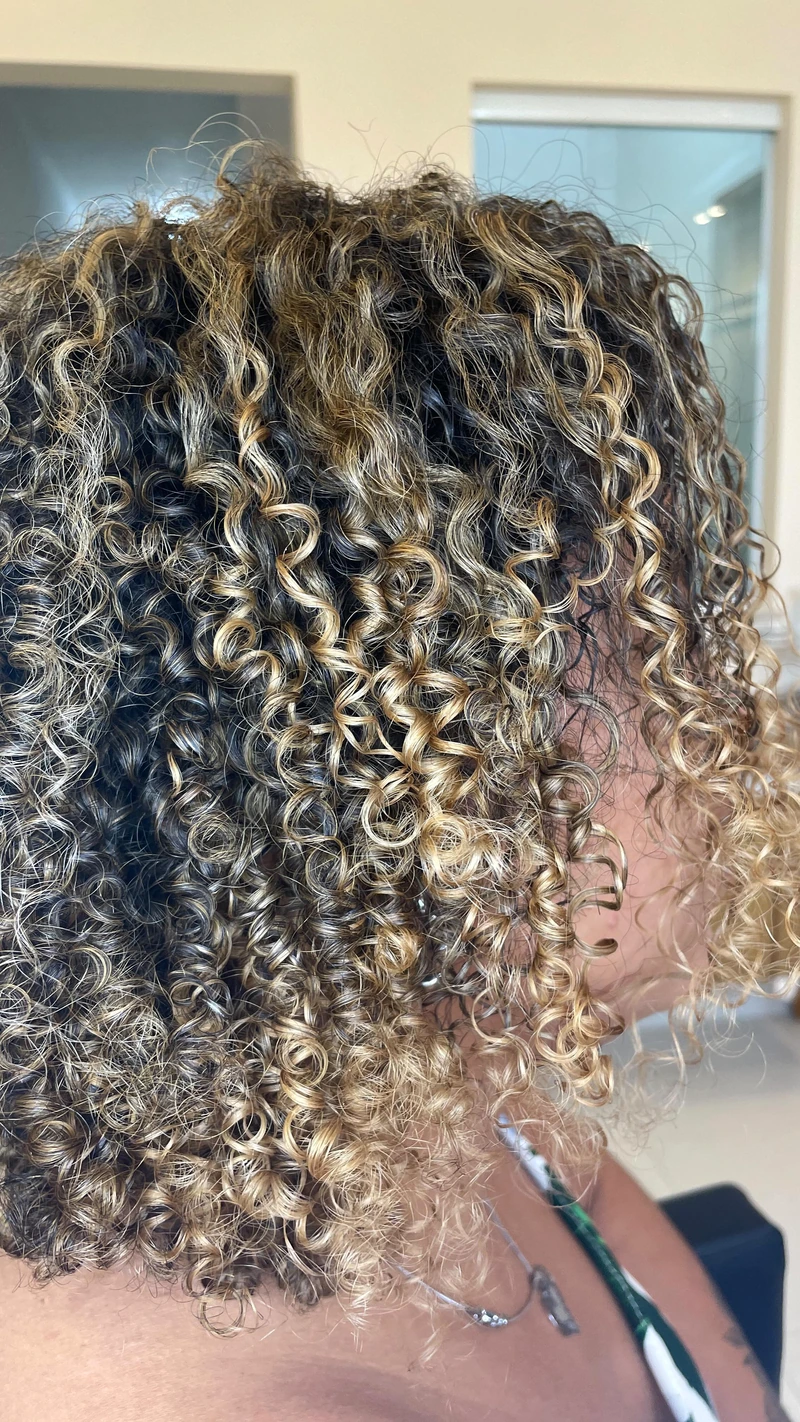 Detalhe de cachos curtos com mechas claras.