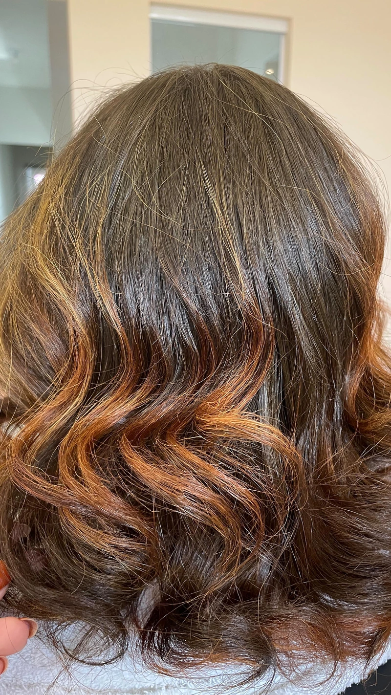 Resultado de cabelo castanho com reflexos caramelo e ondas, visto de costas.
